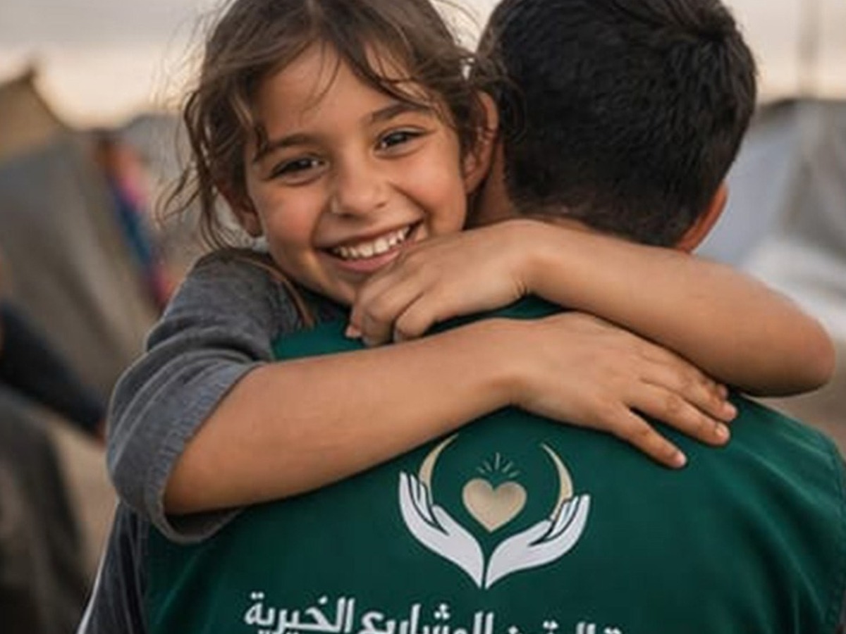 طفلة تحتضن أحد العاملين في الجمعية